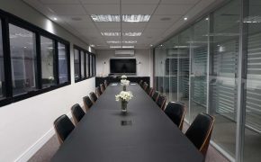 Sala de reunião Herus Hiru na sede Fismatek, com mesa para 16 pessoas e estrutura de vidro.