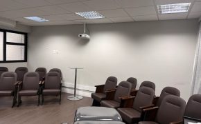 Sala Francisco, auditório de treinamentos da Fismatek com poltronas reclináveis, projetor e maca de equipamento em primeiro plano