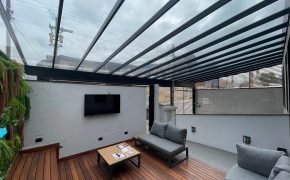Lounge externo coberto da unidade Fismatek Cisper com deck de madeira, sofás e TV