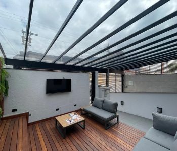Lounge externo coberto da unidade Fismatek Cisper com deck de madeira, sofás e TV