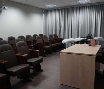 Vista lateral da Sala Francisco com fileiras de poltronas para treinamento e maca de equipamento ao fundo